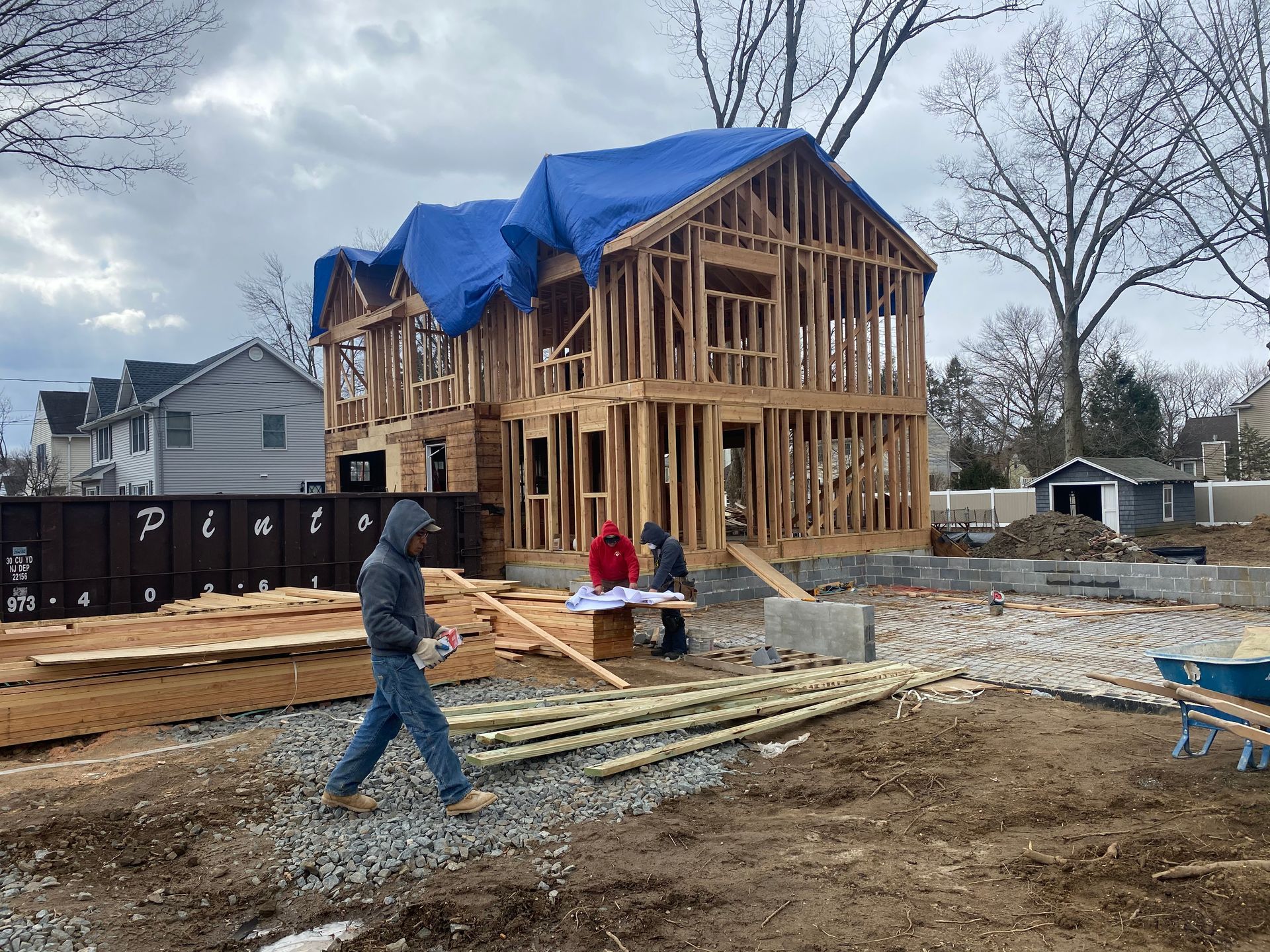 A man is walking in front of a house under construction.
