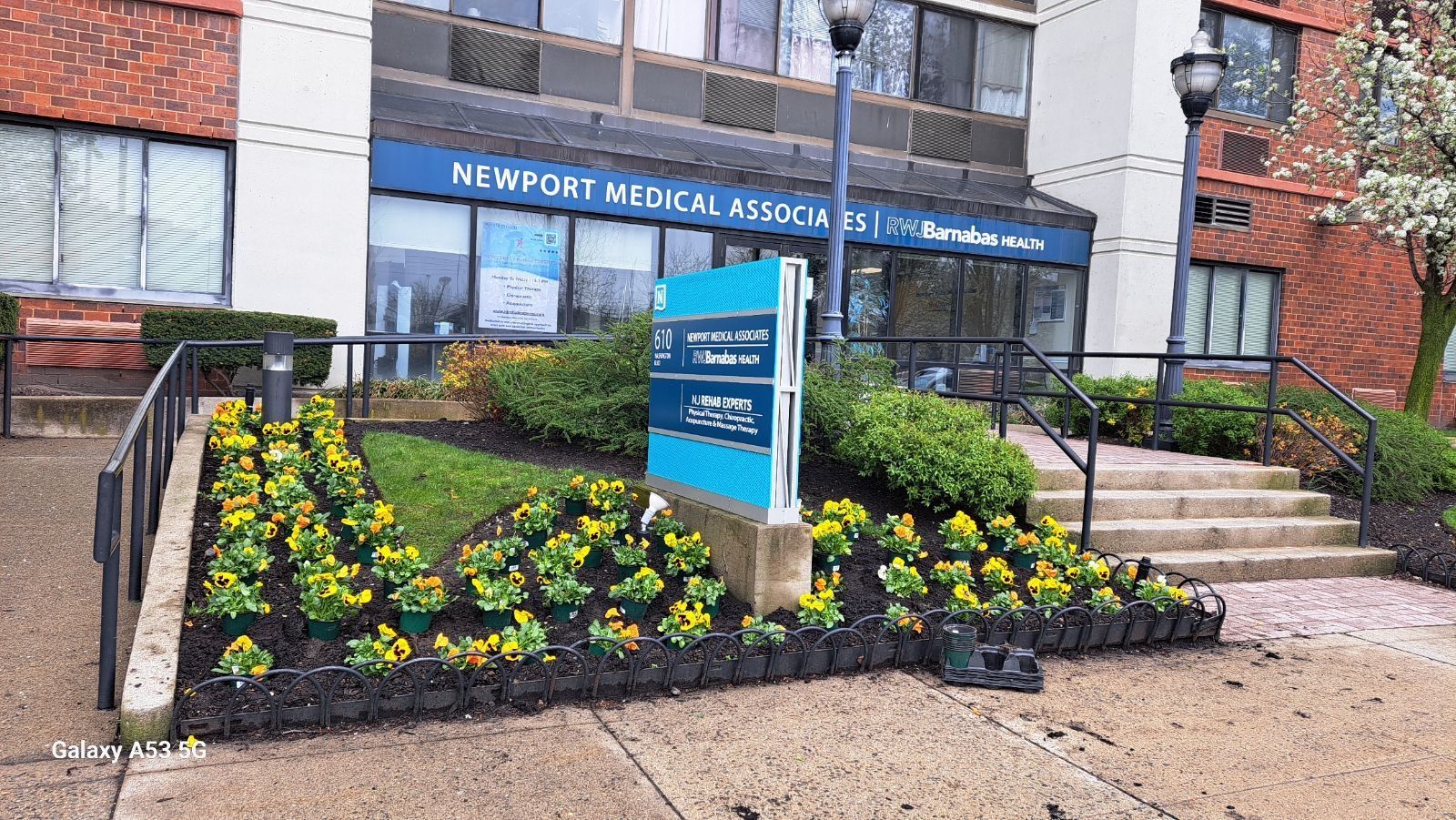 A building with a sign in front of it and flowers in front of it.