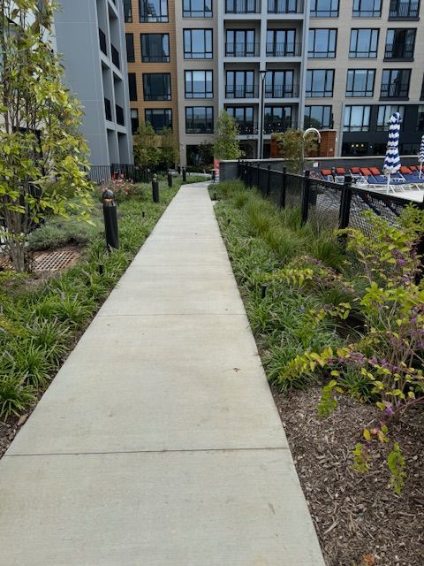 A concrete walkway leading to a building with a pool in the background.