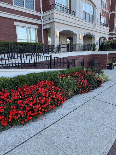 A building with a fence and flowers in front of it