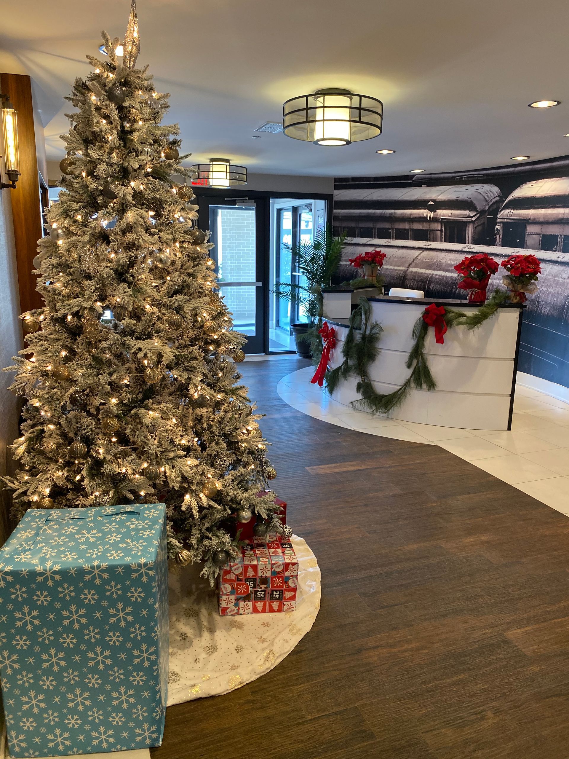 A christmas tree with gifts underneath it in a hallway