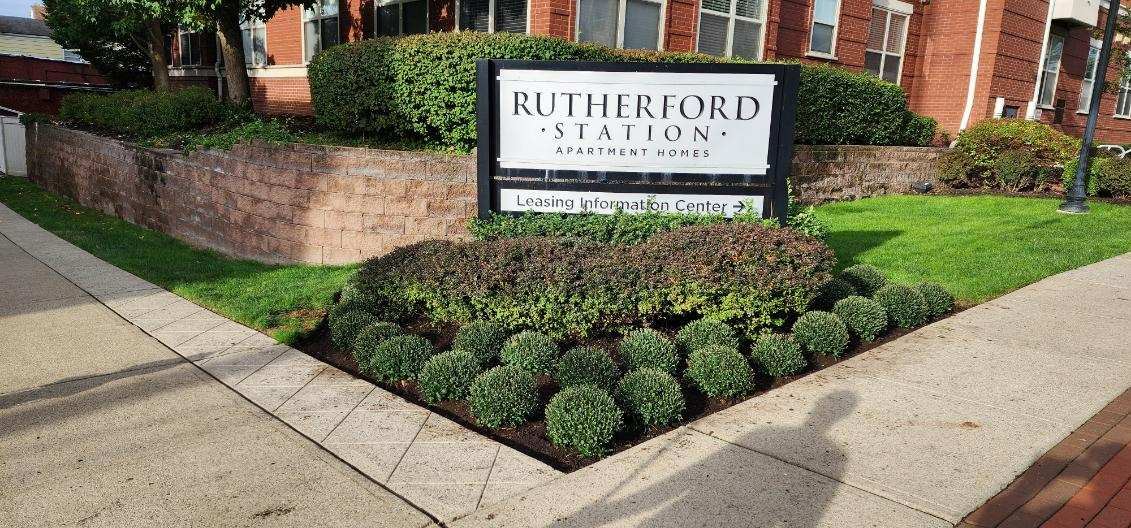 A sign for Rutherford station is sitting in front of a brick building.