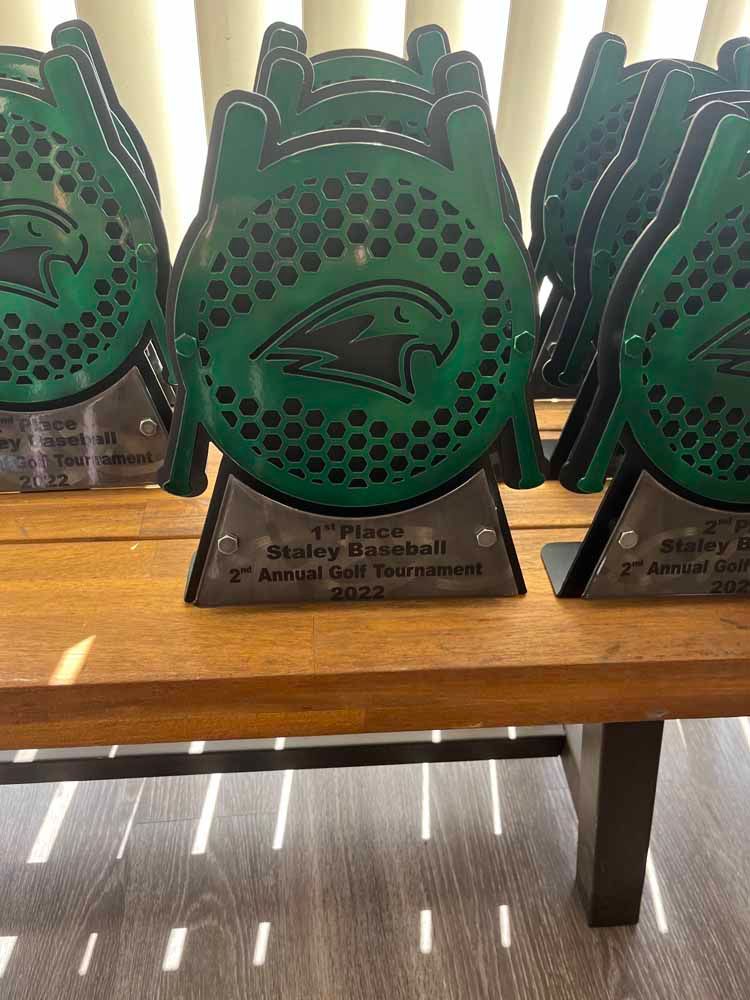 A row of green trophies sitting on top of a wooden table.