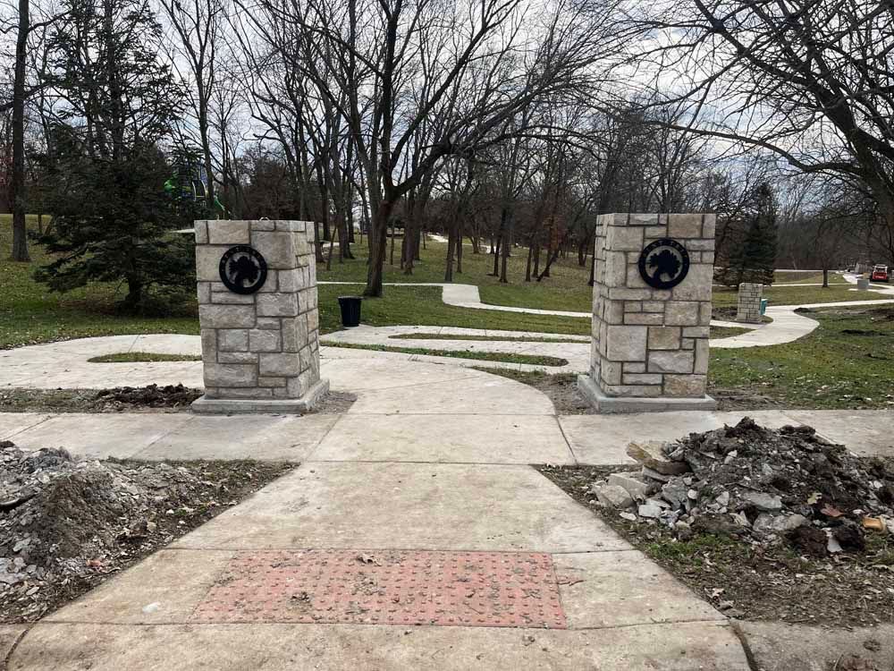 There are two stone pillars in the middle of a walkway in a park.