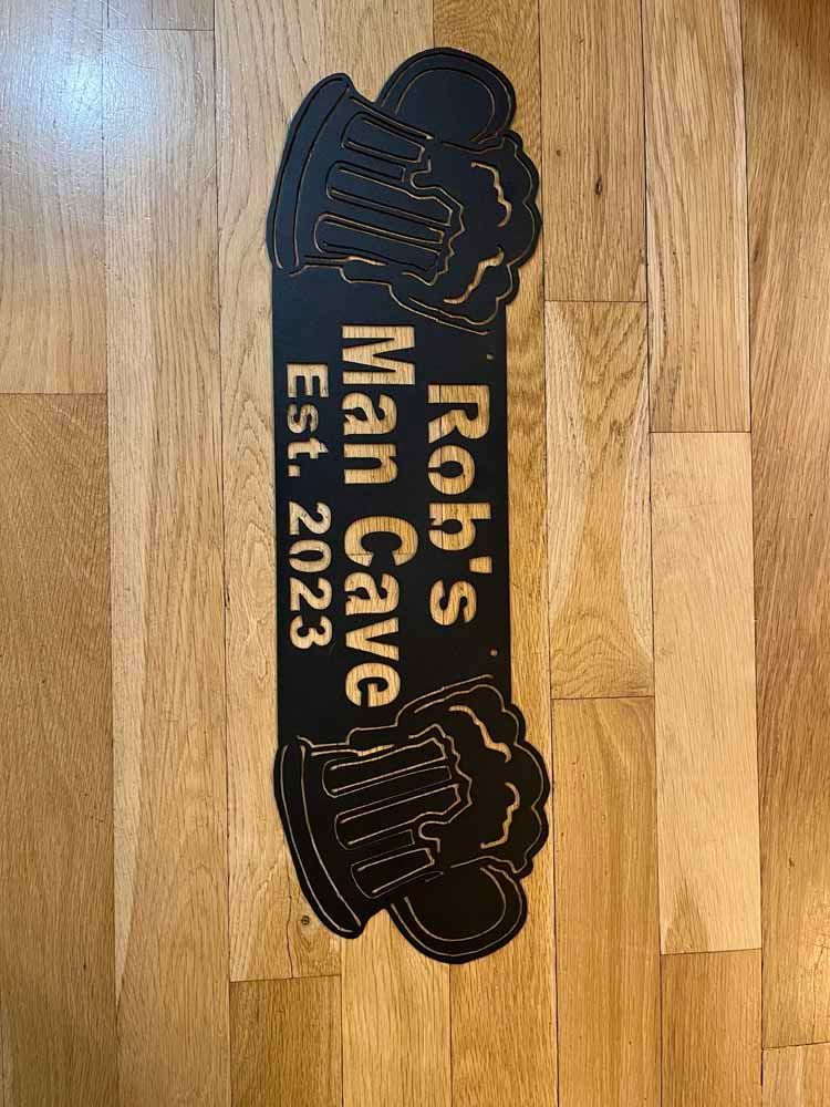 A sign that says rob 's man cave is on a wooden floor.