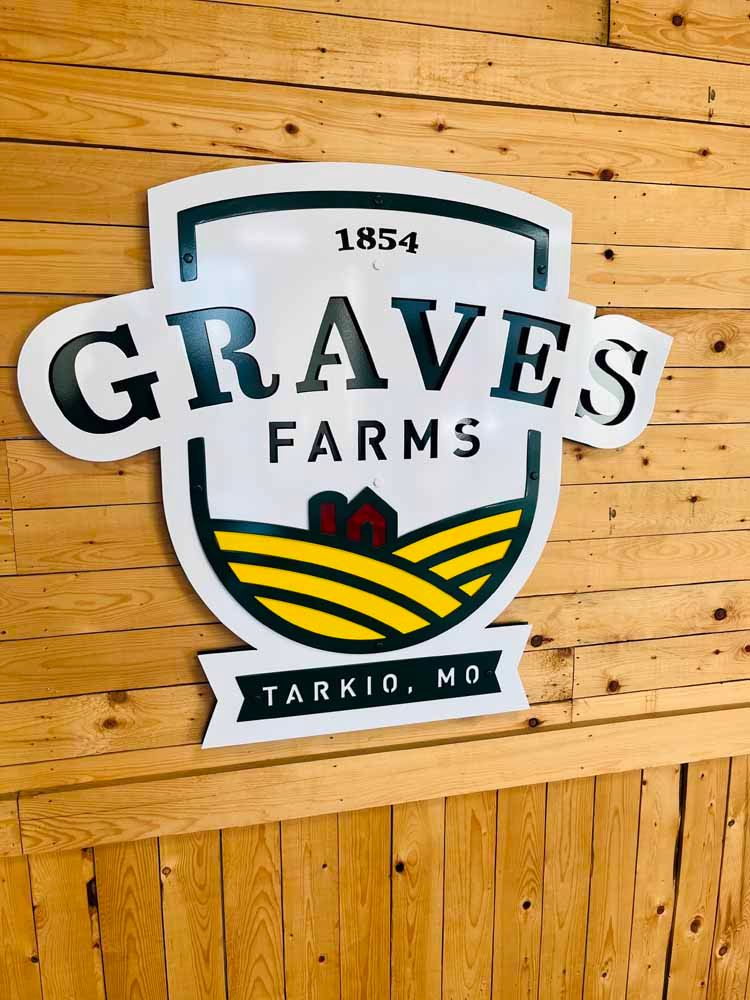 A graves farms sign is hanging on a wooden wall.
