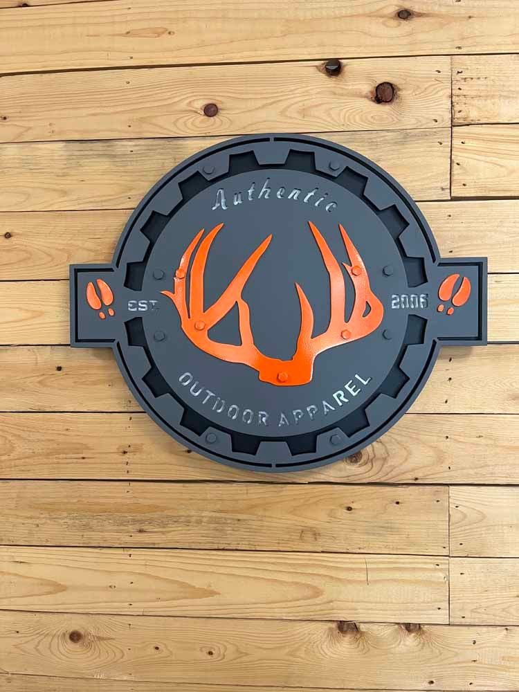 A sign with a deer head on it is on a wooden wall.