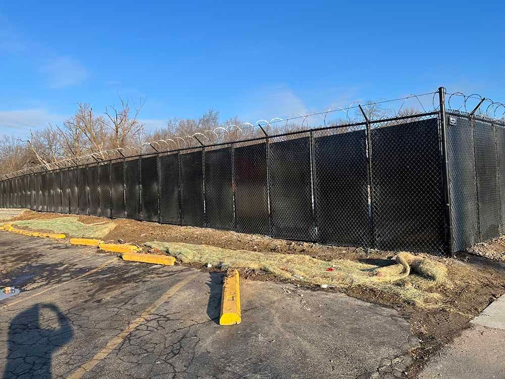 A barbed wire fence is surrounding a parking lot.