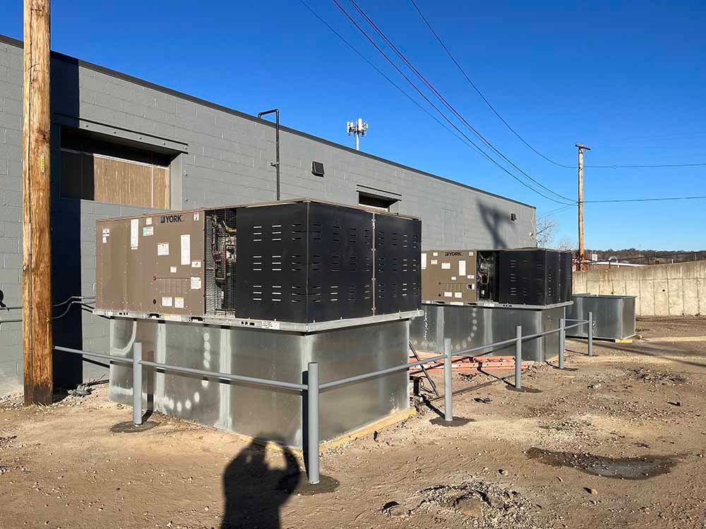 A row of air conditioners are sitting outside of a building.