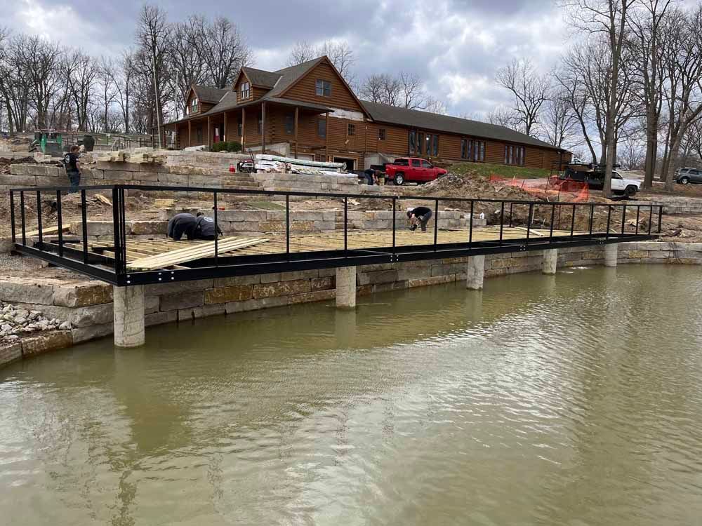 A bridge over a body of water with a house in the background.