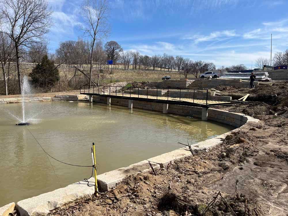 There is a fountain in the middle of the pond.