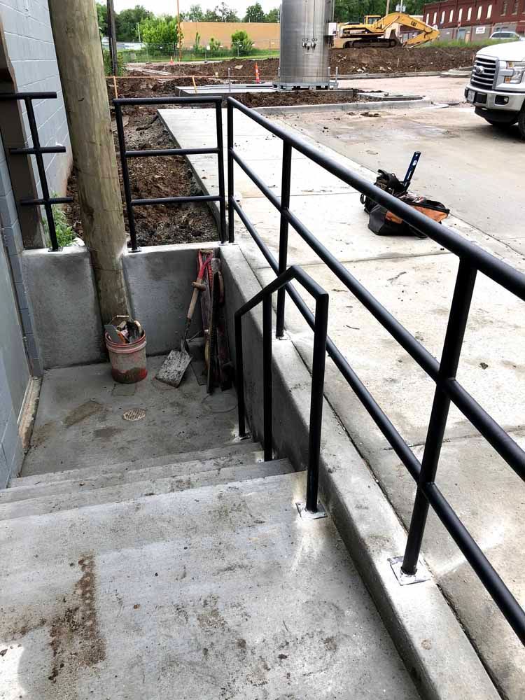 A staircase with a railing and a bucket on the side of it.