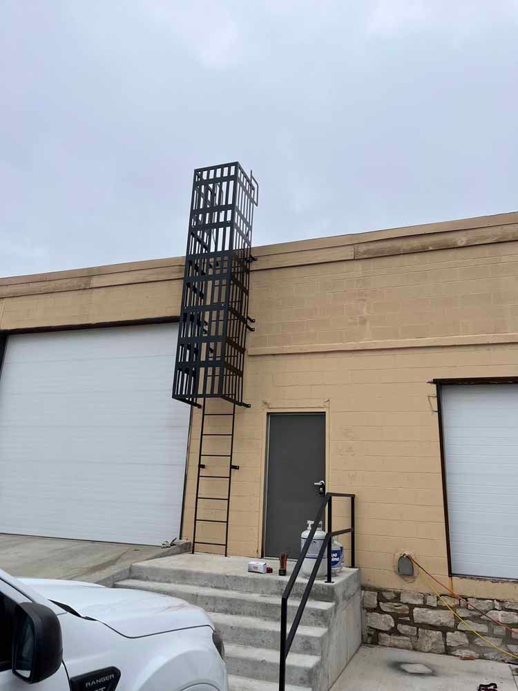 A white truck is parked in front of a building with a fire escape.