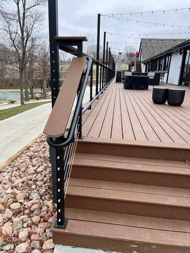 A wooden deck with stairs and a metal railing.