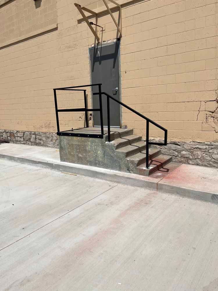 A set of stairs leading up to a door with a metal railing