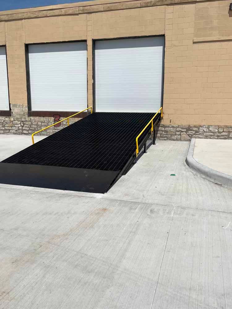 A black ramp with a yellow railing is in front of a building.