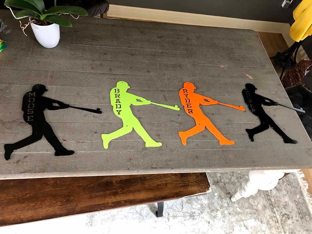 A wooden table with three silhouettes of baseball players on it.