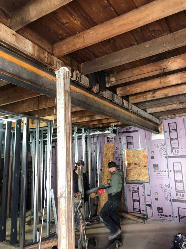A group of construction workers are working on a house under construction.