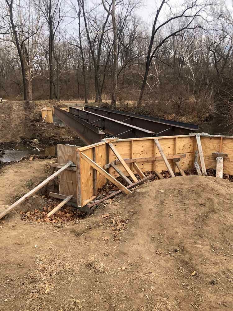 A bridge is being built over a river in the woods.