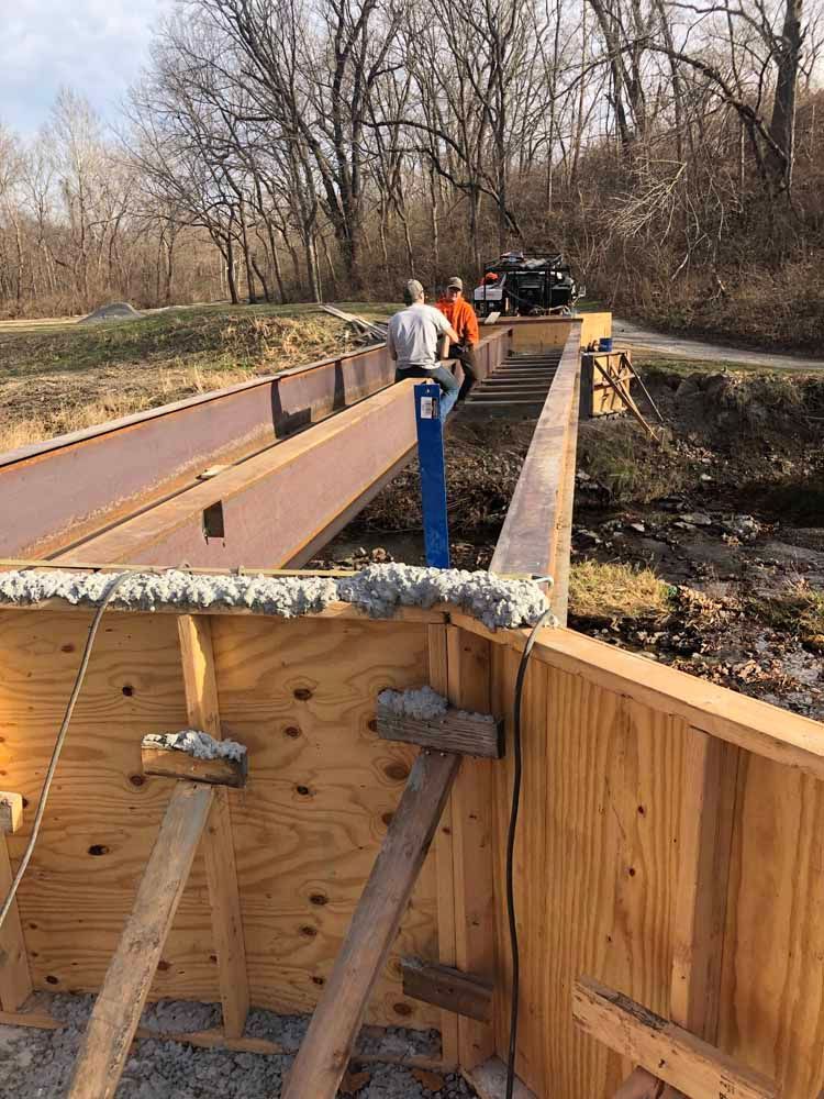 A group of men are working on a wooden bridge.