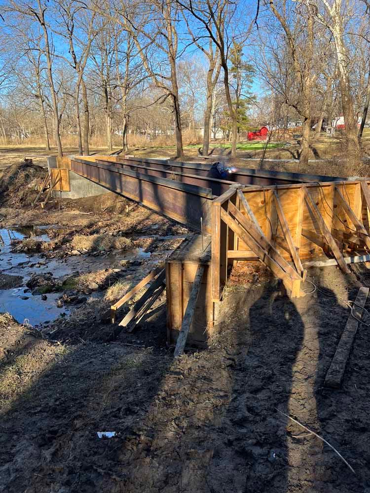 A bridge is being built in the middle of a muddy field.