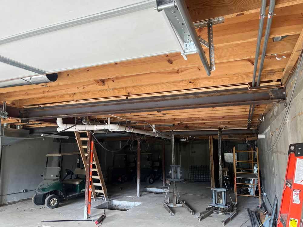 A garage under construction with a golf cart and a ladder.