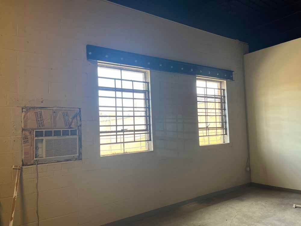 A room with two windows and an air conditioner in it.