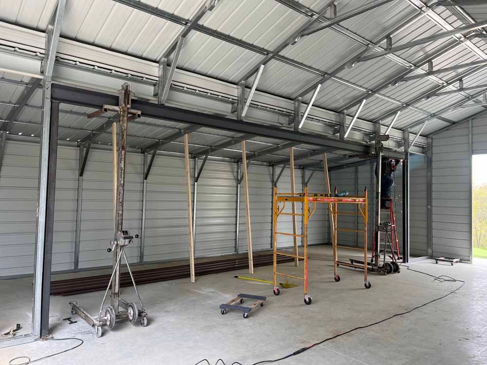 A man is standing on a ladder in a large metal building.