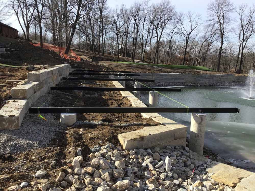A fountain is being built next to a pond in a park.