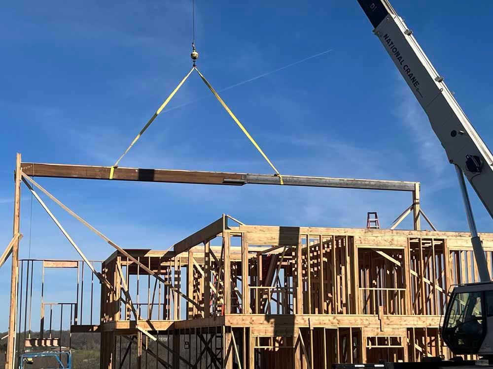 A crane is lifting a piece of wood over a building under construction.