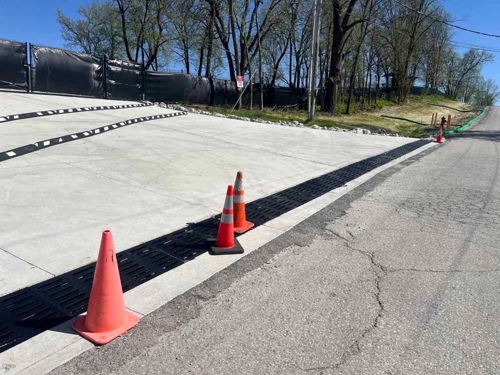 Three orange traffic cones are sitting on the side of a road.