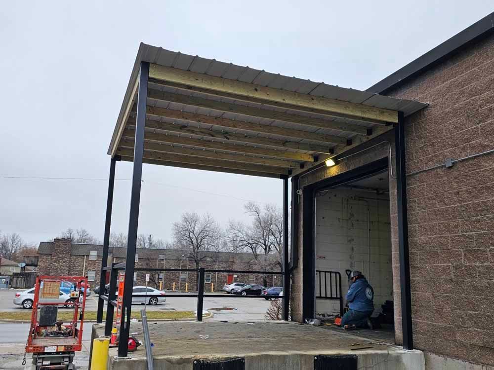 A man is welding a metal structure on the side of a building.
