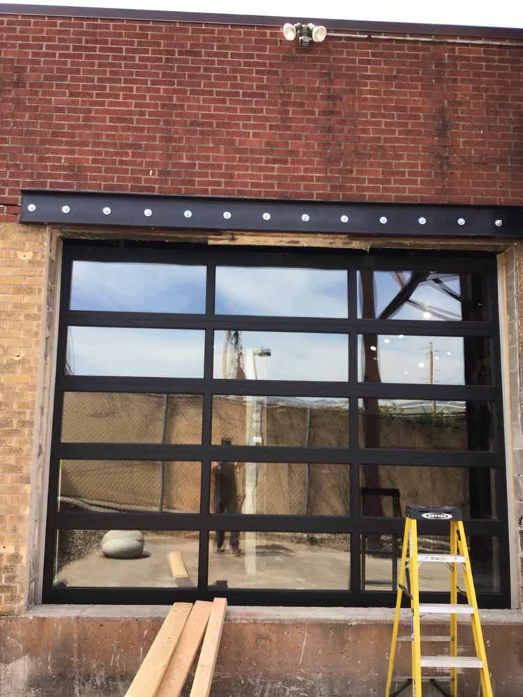 A large garage door is being installed on a brick building.