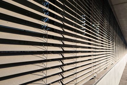 Close-up of horizontal window blinds with light and shadow in a long corridor