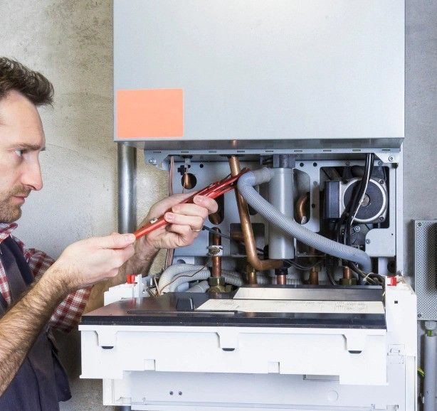 a man is working on a boiler with a screwdriver