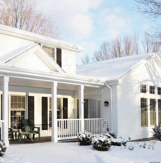 A white house with a porch covered in snow