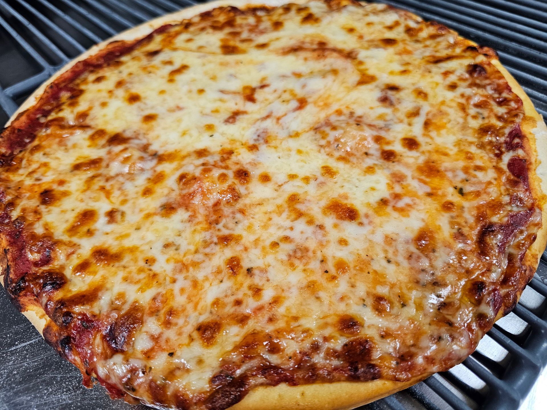 A pizza with cheese and tomato sauce is sitting on a grill.