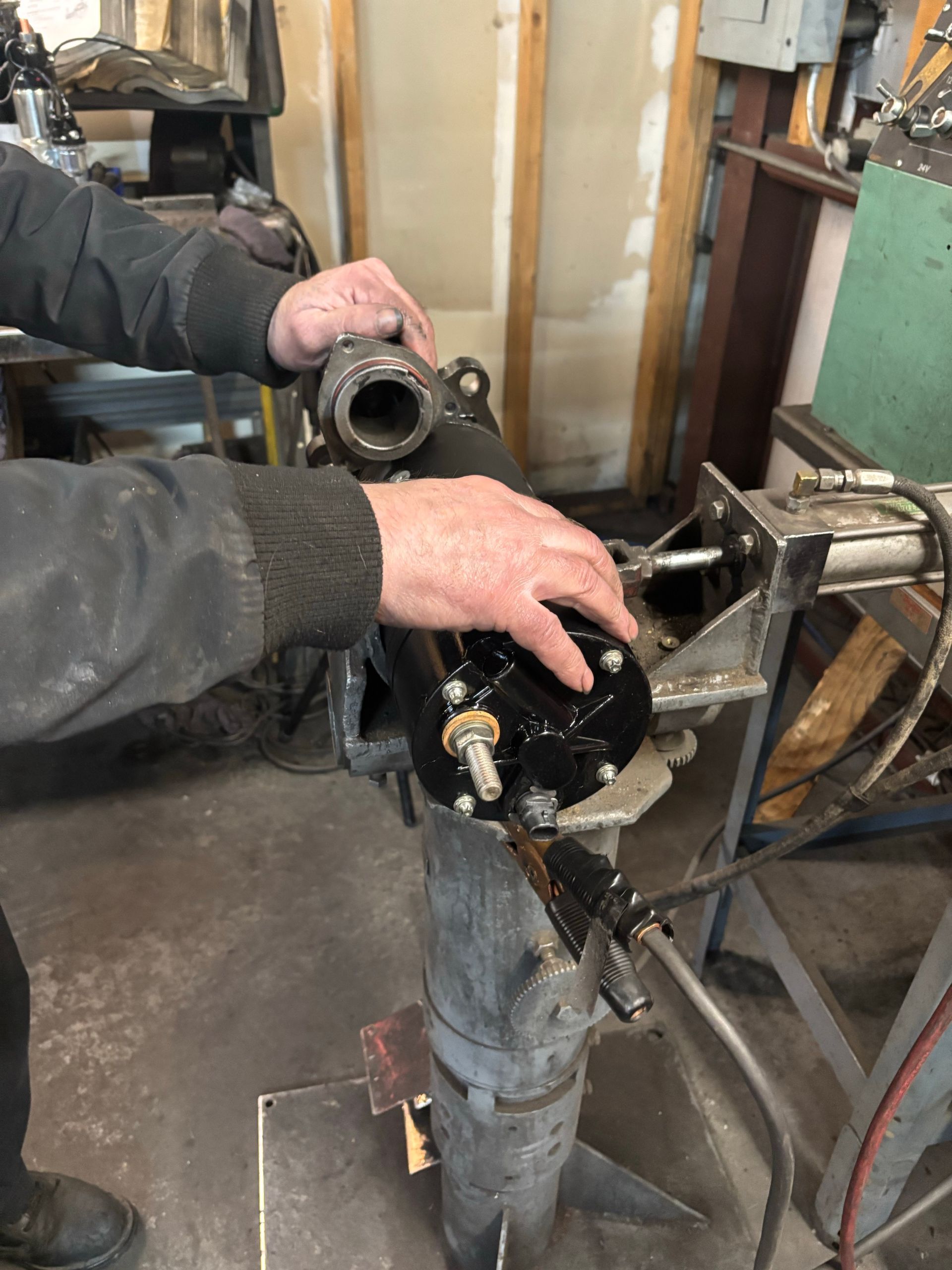 A man is working on a piece of metal in a garage.