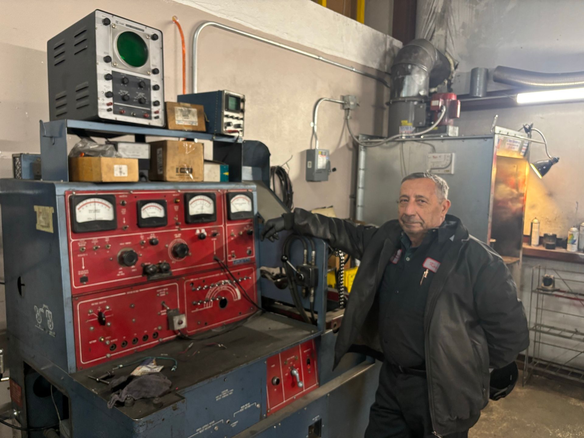 A man is standing in front of a machine in a garage.