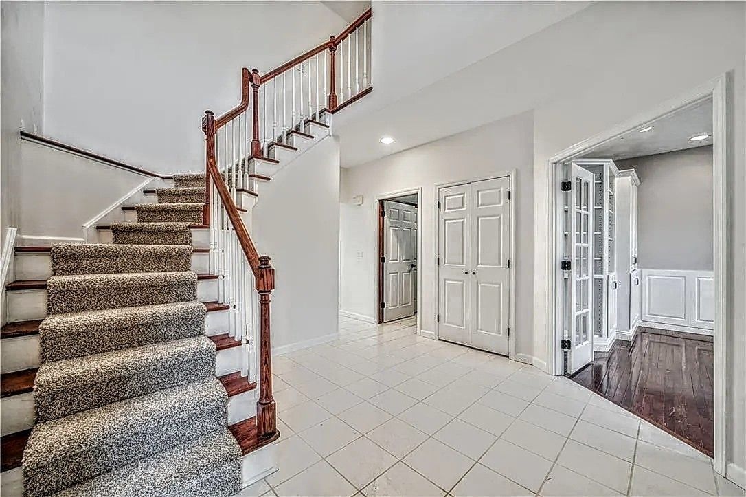 Interior view of a white room with dark floors, a partially frosted glass door, and white cabinets.