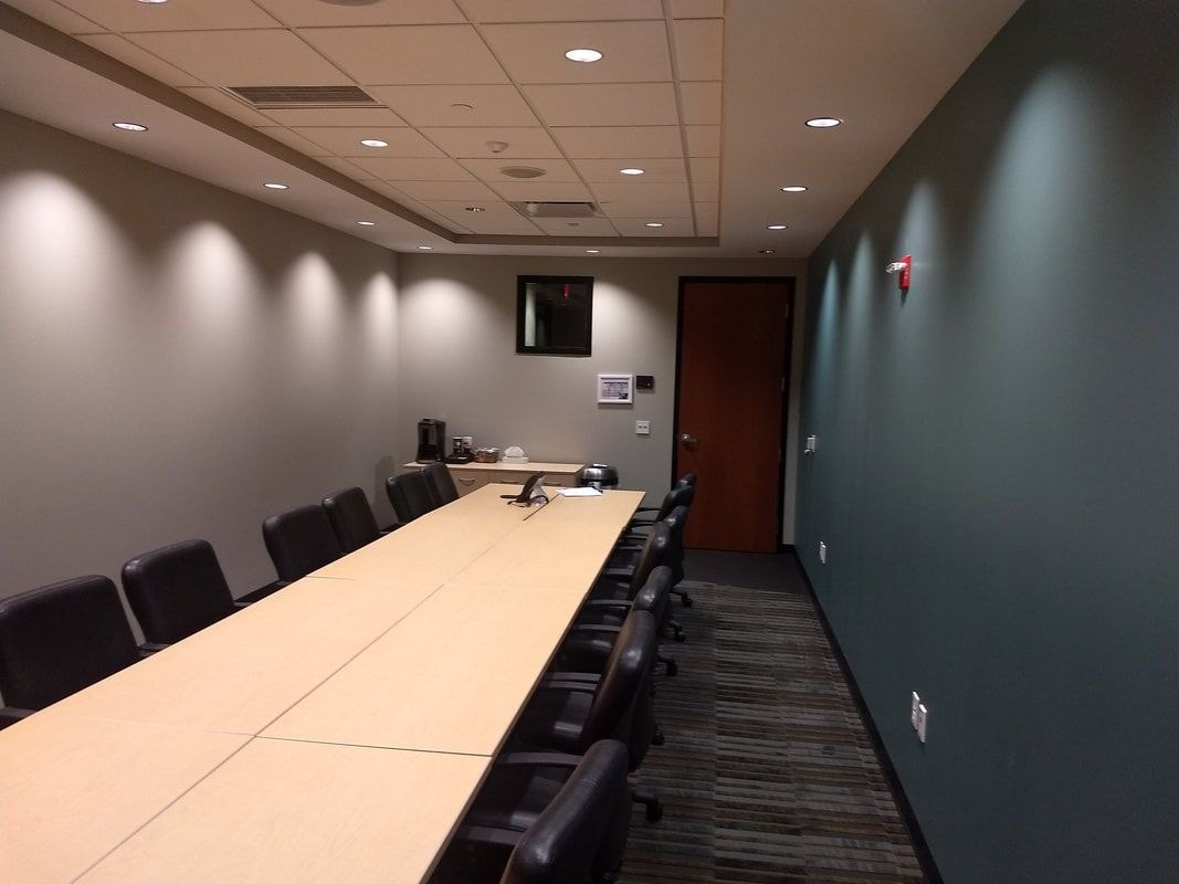 Conference room with long table, chairs, and dark blue-green walls.