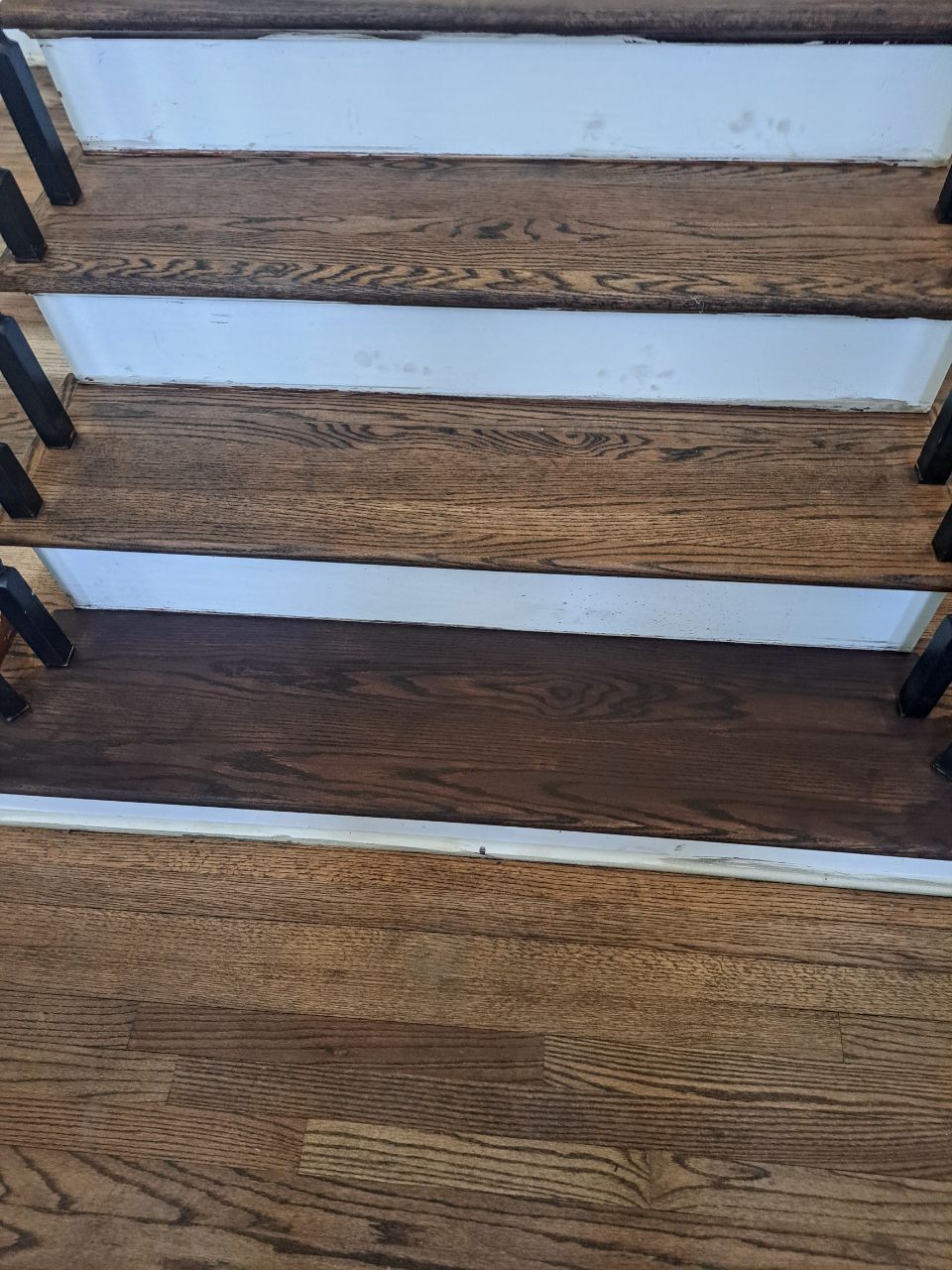 Wooden staircase with dark stained treads and white risers. Black metal balusters.