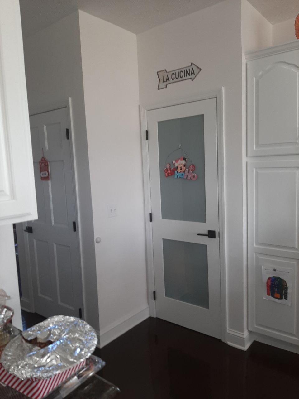 White pantry door with frosted glass and black handle, arrow sign above.