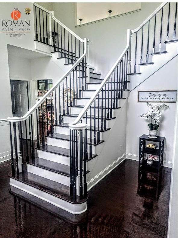 Staircase with black and white railings and steps, dark wood floor, potted plant on a small table.
