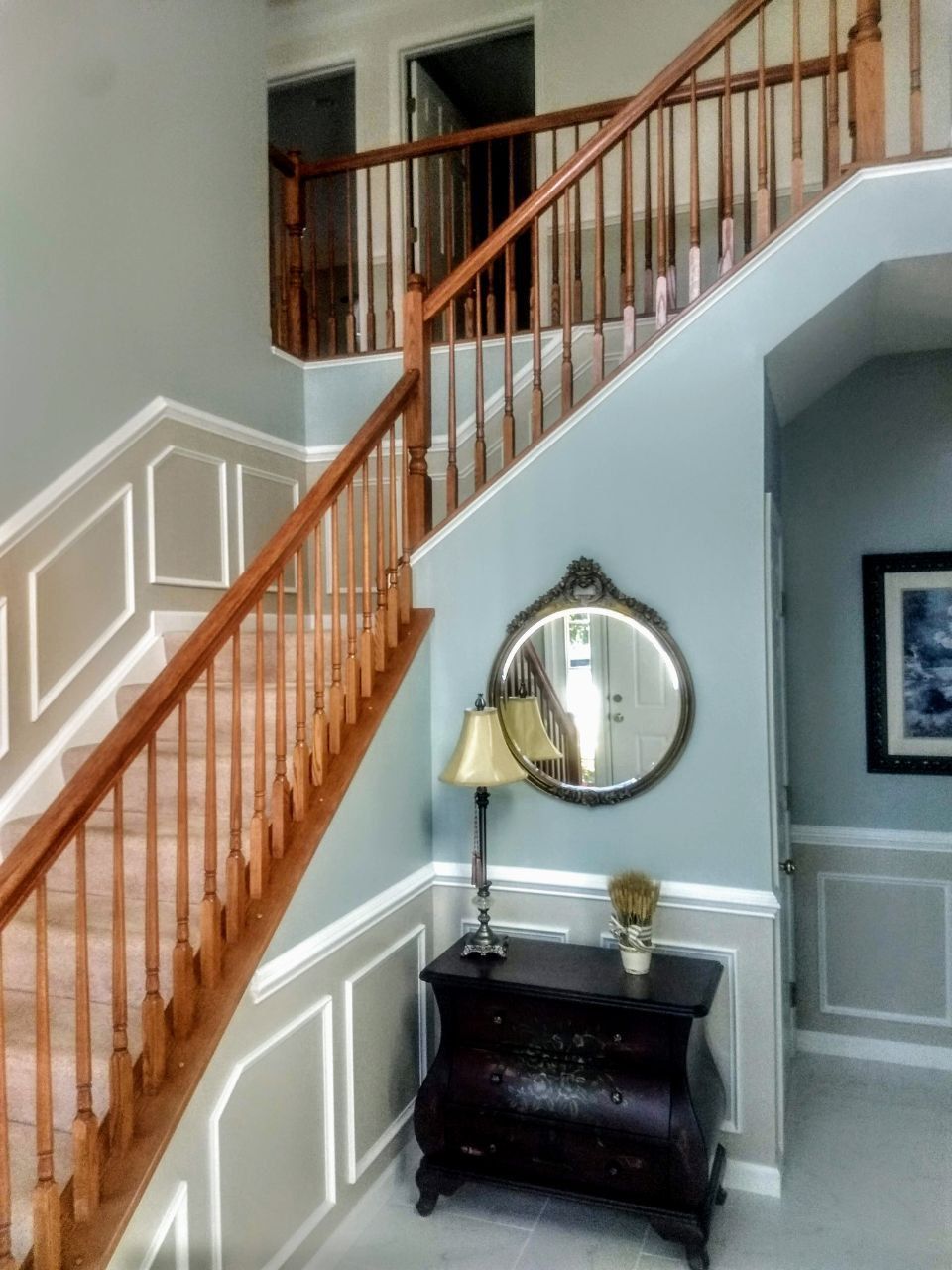 Wooden staircase with blue walls, decorative trim, and antique furniture.