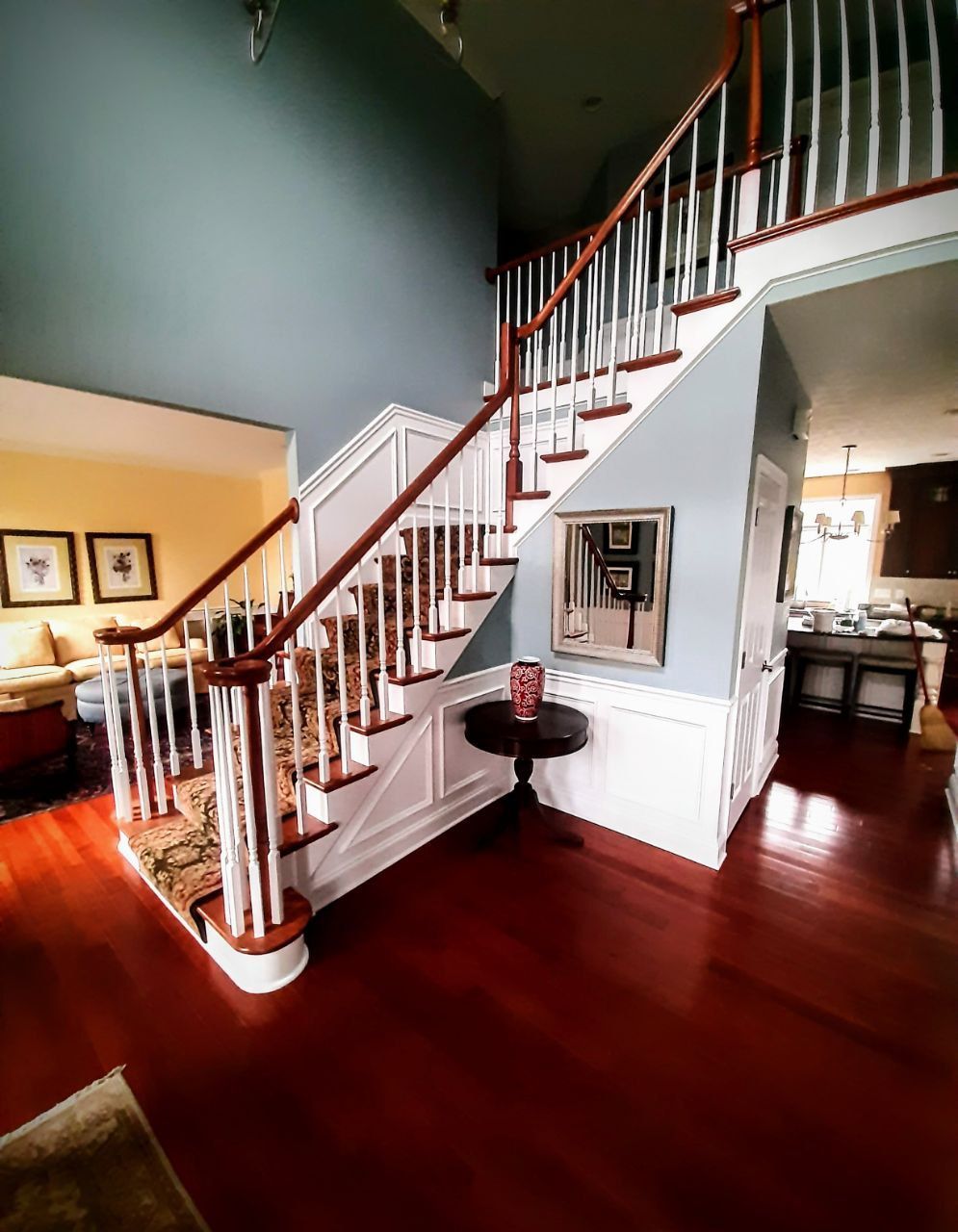 A two-story entryway with a staircase and a small round table. The walls are blue and white.