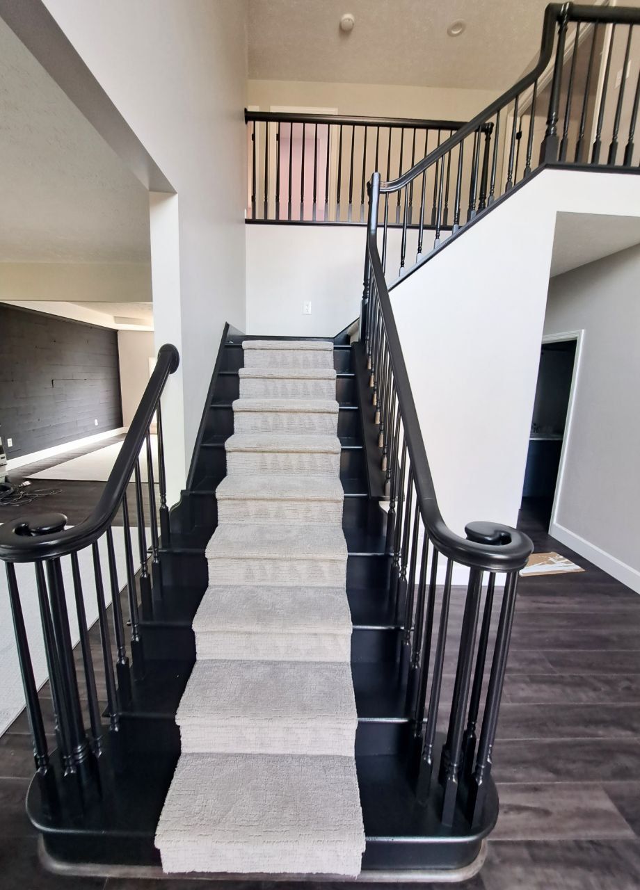 Black and white staircase with carpet runner, leading to a second floor landing.