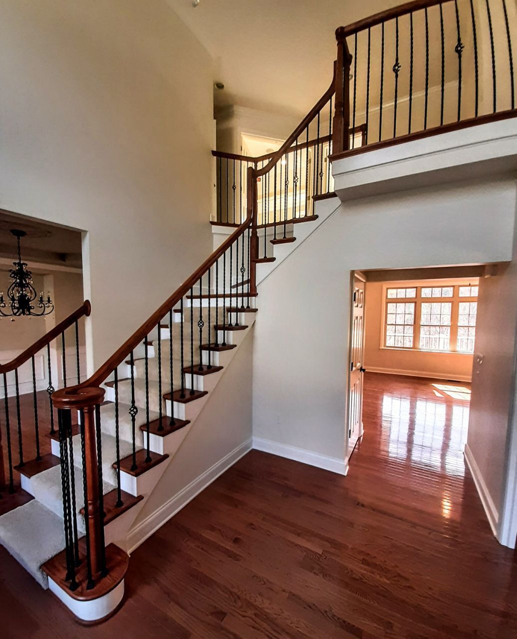 Interior of a home with a staircase, hardwood floors, and bright lighting.