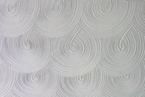 White textured wall with a swirling, looped pattern.
