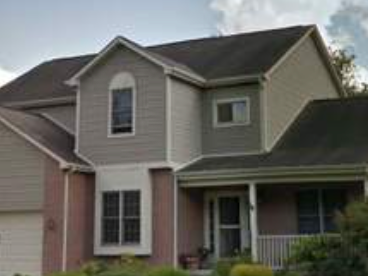 Two-story house with gray siding, brick accents, and a front porch.